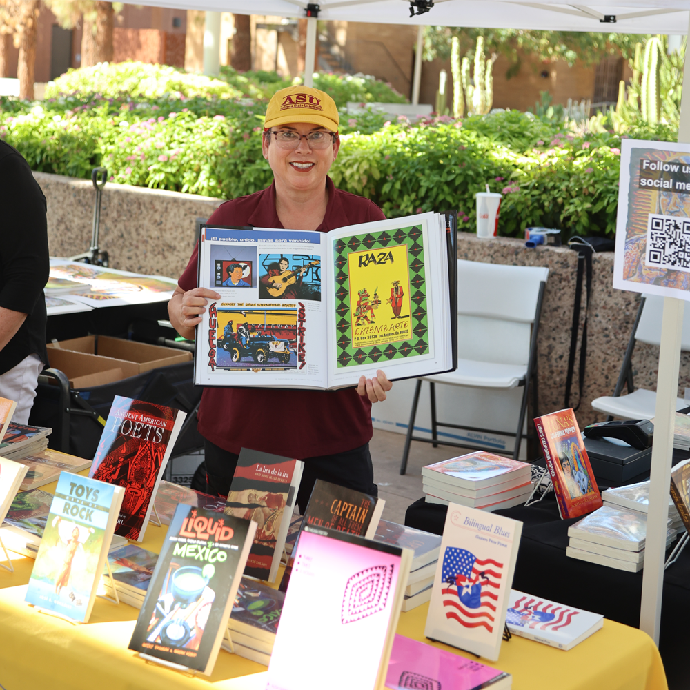 Woman stands wearing yellow hat while holding a large opened book.